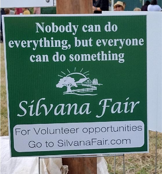 a sign asking for volunteers to help with the fair