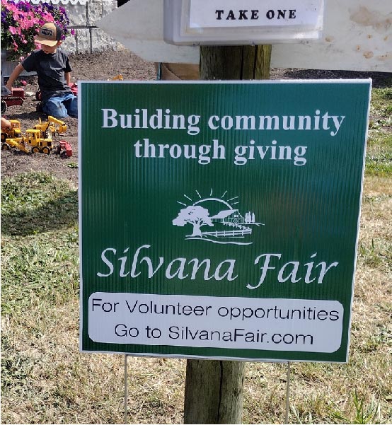a sign asking for volunteers to help with the fair