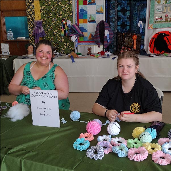 two adult women demonstrating crocheting